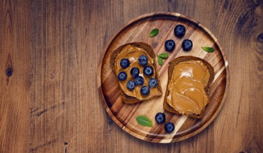 Rye bread with peanut paste and fresh blueberries, top view, no people