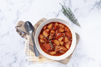 Meat goulash with potatoes and carrots, sweet peppers, in a saucepan, top view, traditional