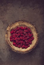 Fresh raspberries in a wooden bowl, food background, concept, food styling, on a dark table, top