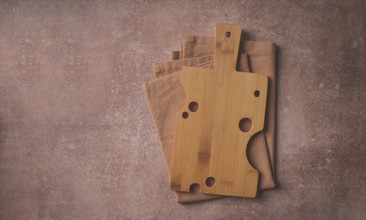 Wooden cutting board, rectangular with handle, cheese shape with holes, on a kitchen towel, top