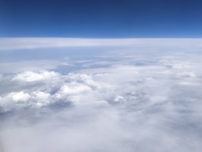 View from an airplane of closed cloud cover in it white bright cluster clouds cirrus clouds on the
