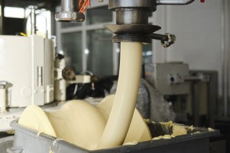 Automated food production machine dispensing butter into container in industrial manufacturing