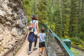 Mother and son holding hands are enjoying a hike along the scenic johnston canyon trail in banff