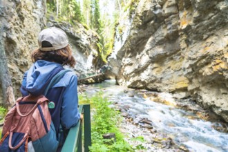 Female tourist with a backpack admiring the breathtaking turquoise waters flowing through the rocky