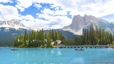 Canoeing tourists glide across the turquoise waters of emerald lake, framed by a wooden bridge,
