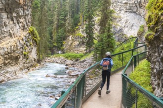 Female tourist with a backpack walking along a metal catwalk, taking in the scenic views of