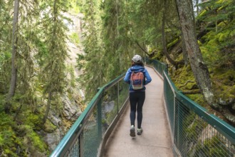 Female tourist with backpack walking on the johnston canyon catwalk trail in banff national park,