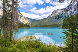 Tourists are canoeing on the turquoise waters of emerald lake, surrounded by lush vegetation and