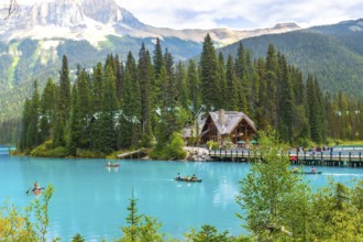 Tourists are canoeing on the turquoise waters of emerald lake with a beautiful wooden lodge and the