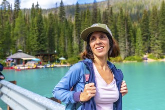 Female hiker wearing a baseball cap and backpack standing near the turquoise waters of emerald