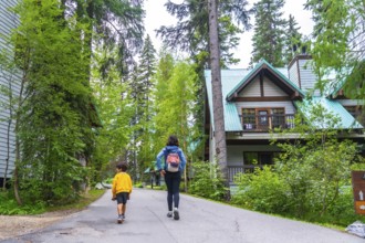 Mother and son walking away on a paved path near the emerald lake lodge in banff national park,
