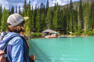 Tourist standing on a bridge admires the turquoise waters of emerald lake, surrounded by lush