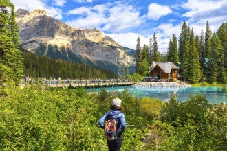 Female tourist with a backpack admiring breathtaking turquoise waters of emerald lake, featuring an
