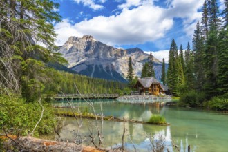 Wooden lodge reflecting in turquoise water with president range mountains towering behind and