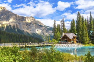 Wooden lodge sitting on the shore of a turquoise lake reflecting the surrounding lush vegetation