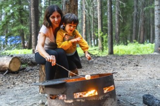 Mother and son roasting marshmallows over a campfire in banff national park, alberta, enjoying a