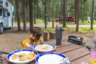 Young camper giving a thumbs up after enjoying a delicious barbecue meal at a campsite in banff