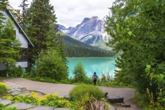 Tourist with a backpack is enjoying the breathtaking view of the turquoise waters of emerald lake,