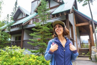 Female tourist wearing a baseball cap and backpack is arriving at emerald lake lodge in yoho