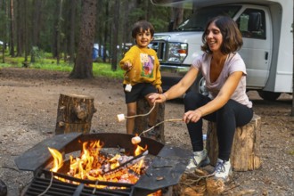 Mother and son roasting marshmallows over a campfire near their campervan in banff national park,