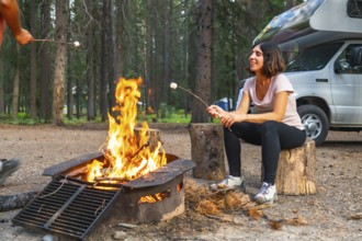 Tourists are roasting marshmallows over a campfire near their campervan in banff national park,