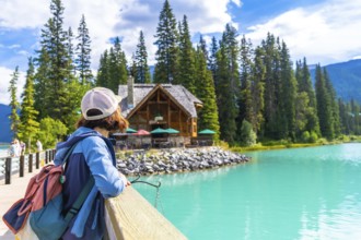 Tourist with a backpack enjoying breathtaking views of turquoise waters at emerald lake, framed by