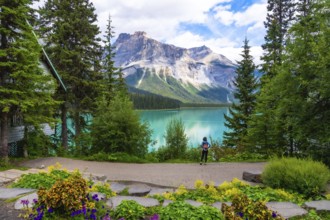 Tourist with a backpack admiring the breathtaking turquoise waters of emerald lake and the imposing