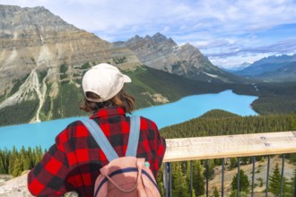 Female hiker enjoying breathtaking view of turquoise peyto lake and surrounding mountains in banff