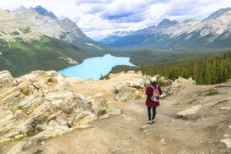 Female hiker admiring the stunning turquoise hues of peyto lake, surrounded by majestic mountains