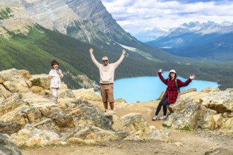 Tourists raising their arms in excitement while admiring the stunning turquoise peyto lake from a