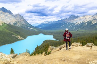 Hiker enjoying breathtaking view of turquoise peyto lake and surrounding rocky mountains in banff