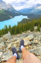 Hiker resting on rocky terrain while enjoying breathtaking views of turquoise peyto lake,