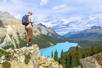 Hiker standing on a cliff edge, soaking in the breathtaking panoramic views of turquoise peyto