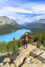Female hiker with a backpack standing on a rocky cliff, enjoying the stunning panoramic view of