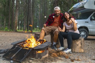 Tourists roasting marshmallows in banff national park, alberta, enjoying a cozy evening by the