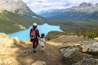 Mother and child admiring the stunning turquoise waters of peyto lake from a scenic viewpoint in