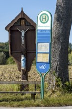 MVV bus stop at a traditional field cross, wayside cross, bench and oak (Quercus) in a field,
