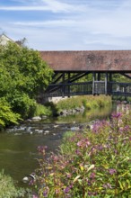 Covered footbridge over the Kronach river, hospital bridge, Blooming flowers on the shore, Kronach,