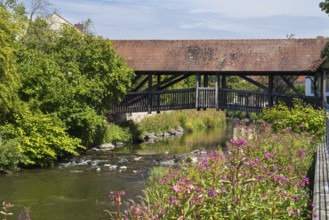 Covered footbridge over the Kronach river, hospital bridge, Blooming flowers on the shore, Kronach,