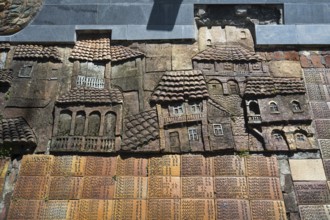 Stone relief with architectural details of traditional houses on a wall, commemoration of World War