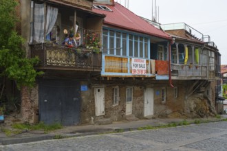 Dilapidated residential buildings with sales signs and rustic balconies on a paved street, Old
