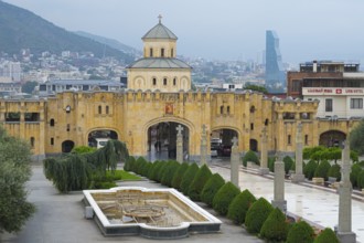 Historic church with yellow tone and modern city in the background against mountain backdrop,