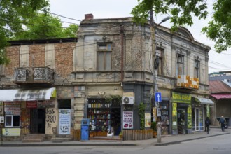 An old building corner with shops on the street, surrounded by trees and power lines, Tbilisi,