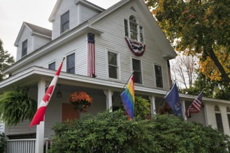Typical American house in autumn, white wooden house with veranda, guest room, rainbow flag,