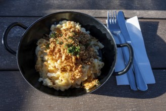 Typical food on an alpine pasture, a portion of cheese patzen or cheese socks in a cast pan,
