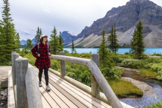 Female tourist with backpack is walking on wooden bridge and enjoying breathtaking view of