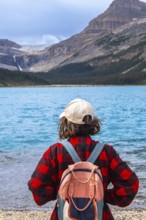 Female hiker with backpack enjoying breathtaking view of turquoise bow lake and crowfoot glacier in