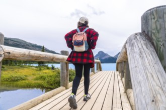 Female tourist walking on wooden bridge enjoying the scenic view of bow lake and surrounding