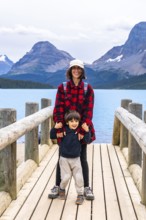 Smiling mother and son embracing the stunning scenery of turquoise bow lake and surrounding