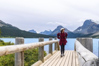 Female tourist walking along a wooden bridge and enjoying the breathtaking view of turquoise bow